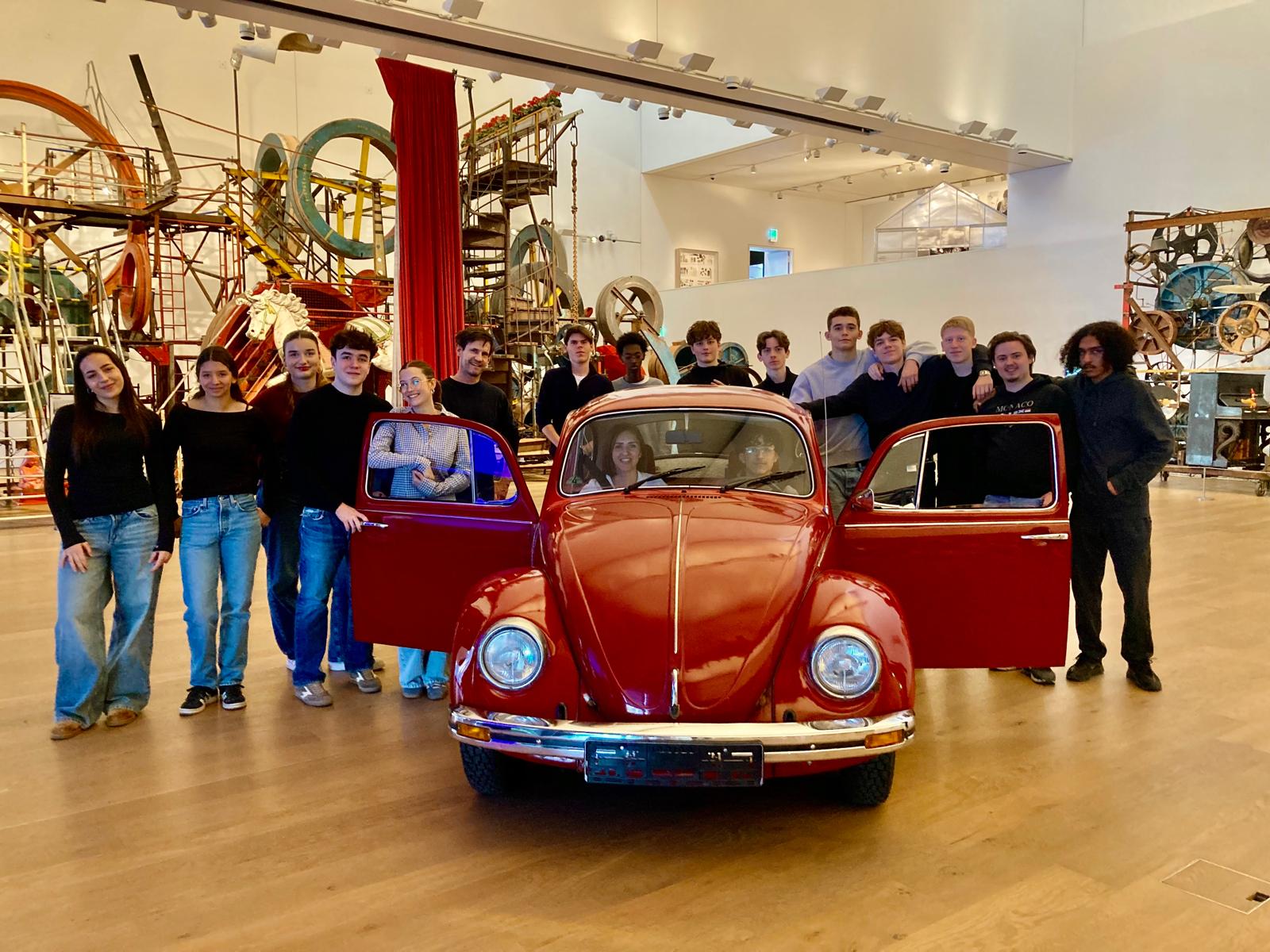 Gruppe hinter einem roten VW Käfer im Museum Tinguely