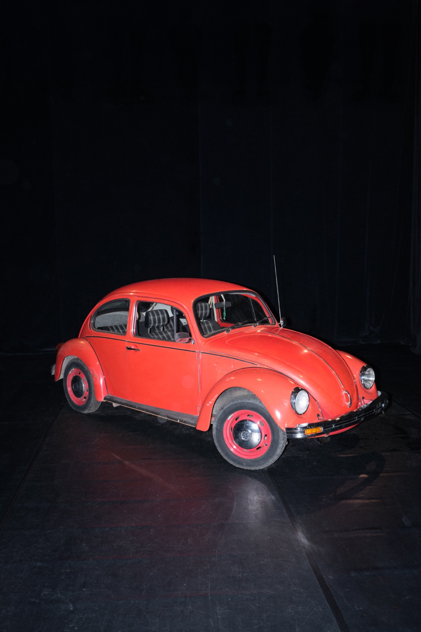 Roter VW Käfer auf einer dunklen Bühne