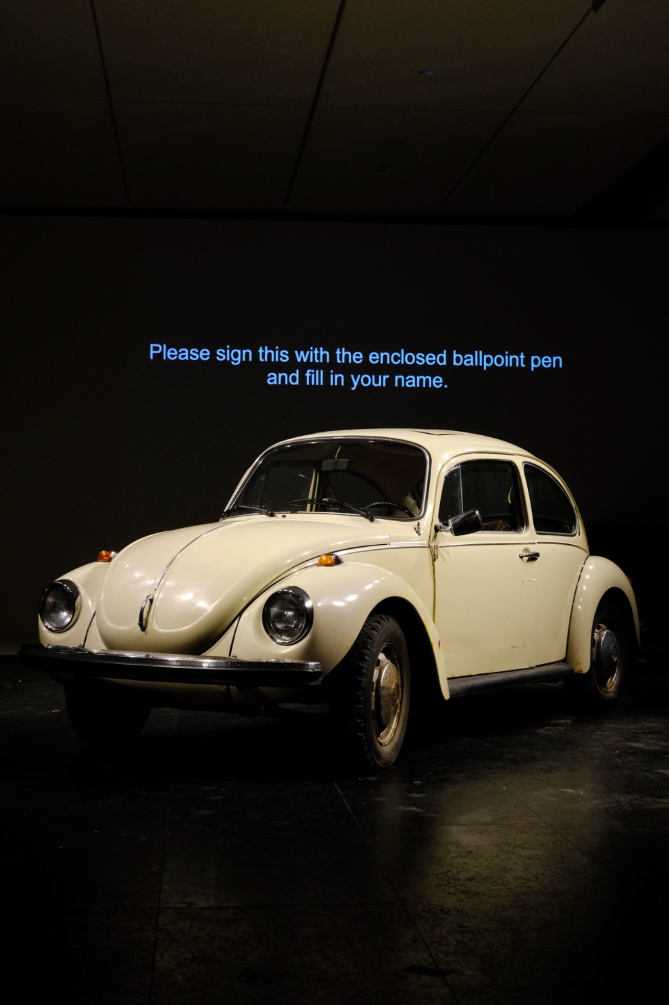 Beiger VW Käfer vor projiziertem englischem Text