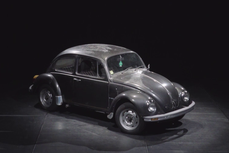 Schwarzer VW Käfer im Licht auf einer dunklen Bühne